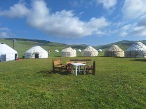 a table and chairs in a field with tents at Anarhan Guesthouse Horse riding to Song-Kol and Kilemche in Kyzart