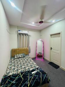 a bedroom with a bed and a pink chair at Royal Stays 2Bed Cozy Apartment in Multan +8 photos