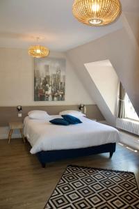 a bedroom with a large bed with blue pillows at Logis Hôtel Restaurant L'Ile de Sées in Macé +30 photos