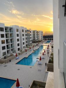 a swimming pool with chairs and umbrellas next to buildings at Studio in Porto Said Compound in Port Said