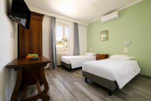 ein Zimmer mit zwei Betten, einem Schreibtisch und einem Fernseher in der Unterkunft Hotel Villa Bonelli in Fiesole + 82 Fotos