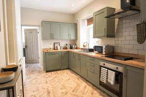 a kitchen with green cabinets and a stove top oven at Park House by Tŷ SA in Aberdare