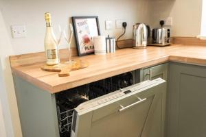 a kitchen counter with a wine bottle and glasses on it at Park House by Tŷ SA in Aberdare