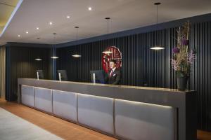 a man in a suit standing behind a reception desk at NH Collection Nürnberg City in Nuremberg