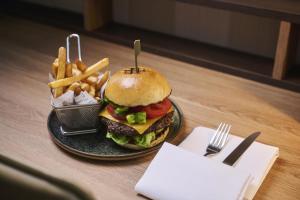 a plate with a hamburger and french fries on a table at NH Collection Nürnberg City in Nuremberg