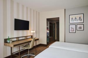 a hotel room with a bed and a desk at NH Collection Nürnberg City in Nuremberg