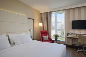 a hotel room with a bed and a desk and a window at NH Collection Nürnberg City in Nuremberg +57 photos