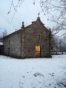 una antigua iglesia de piedra en un campo cubierto de nieve en Casa da Corga, en Portela
