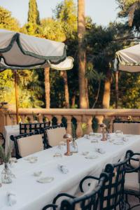 a table with white table cloth and chairs and trees at Château de Valmer in La Croix-Valmer