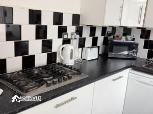 a kitchen with black and white tile on the wall at Warrington 3-Bedroom House Near Birchwood & Omega in Warrington