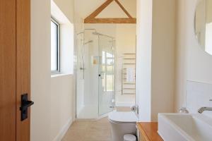 a bathroom with a shower and a toilet and a sink at Scenic Barn Conversion in Rural Shropshire in Craven Arms