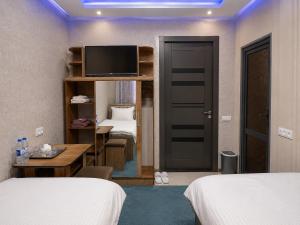 a hotel room with two beds and a television at Zamin Hotel in Shahrisabz
