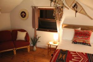 a bedroom with a bed and a chair and a window at Slo-Brome gîte de charme slow life in Lac-Brome