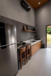 a kitchen with a stainless steel refrigerator and wooden cabinets at Chalé 1 - Vivendas do Caparaó in Pedra Menina