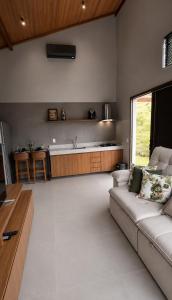 a living room with a couch and a kitchen at Chalé 1 - Vivendas do Caparaó in Pedra Menina