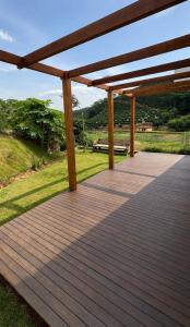 a wooden deck with a pergola in a field at Chalé 1 - Vivendas do Caparaó in Pedra Menina