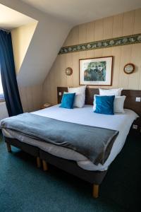 a bedroom with a large bed with blue pillows at L'Auberg'ine - Maison Glenn Anna in Sainte Anne d'Auray