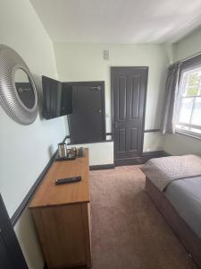 a bedroom with a bed and a desk with a television at The Fox Inn in Steventon