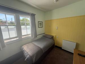 a small bedroom with a bed and two windows at The Fox Inn in Steventon
