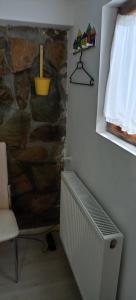 a room with a stone wall and a window and a radiator at Casa cu Turn in Sărata-Monteoru