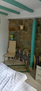 a bed and a chair in a room with a stone wall at Casa cu Turn in Sărata-Monteoru +49 photos