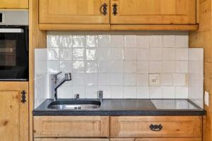 a kitchen with a sink and white tiles at Alpine Studio Flat near Sankt Moritz in Celerina