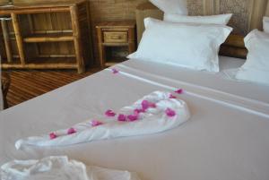 a white bed with a towel with hearts on it at Le Caveau de lemuriens in Nosy Be