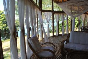 a screened in porch with chairs and curtains at Le Caveau de lemuriens in Nosy Be