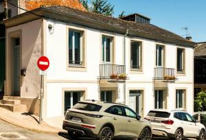 two cars parked in front of a white house at A Calexa Sarria nº3 in Sarria