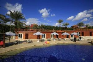 a swimming pool with umbrellas and chairs and a building at Kemzo Hotel in Abū Rawwāsh