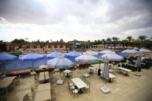a group of umbrellas and tables and chairs with tables and umbrellas at Kemzo Hotel in Abū Rawwāsh