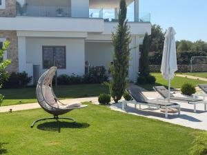 two chairs and an umbrella in a yard with a house at Villa Veneti in Pérdika