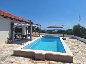a swimming pool with an umbrella next to a house at Relax in Orebić