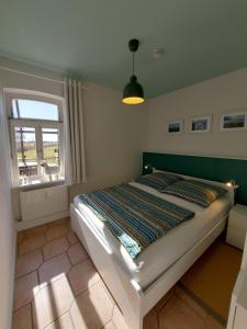 a bedroom with a bed in a room with a window at Lotsenwohnung B-9 in Butjadingen