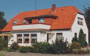 a white house with an orange roof at Ankerplatz H-7 in Butjadingen +2 photos