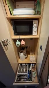 a cupboard with a microwave and other items in it at Port Nan Gael Pods in Pennyghael +24 photos