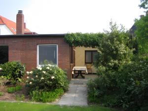 a brick house with a bench in a garden at Kajüte H-8 in Butjadingen