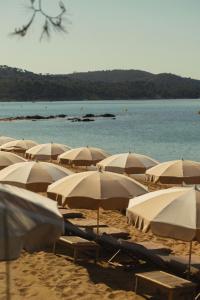 a bunch of umbrellas on a beach with the water at Château de Valmer in La Croix-Valmer