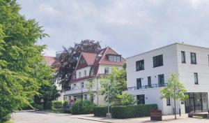 a white building with a red roof next to two white buildings at Apartments Villa Seeblick Travemünde in Travemünde