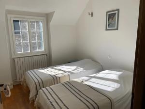 two beds in a room with a window at Les Logis de la Vaucouleurs in Rosay