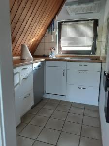 a small kitchen with white cabinets and a window at Haus Maya H-12 in Butjadingen