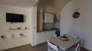 a kitchen with a table with chairs and a tv on the wall at Mastropaolo42 Luxury B&B in Grottaglie
