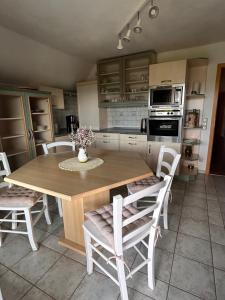 a kitchen with a wooden table and white chairs at Strandläufers Ruhe in Wiepkenhagen
