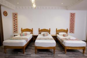 a room with three beds in a room at Mashkobi Buxoro in Bukhara