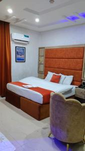 a bedroom with a bed and a chair at Indian Atlantic Hotel & Suites in Agbor