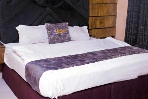 a large bed with white sheets and pillows at Indian Atlantic Hotel & Suites in Agbor