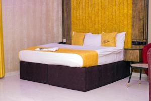 a bedroom with a large bed with a yellow wall at Indian Atlantic Hotel & Suites in Agbor