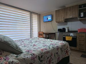 a bedroom with a bed and a kitchen with a television at Departamento Edificio Centro Osorno in Osorno