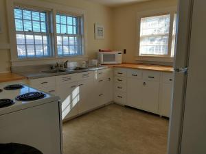 a kitchen with white cabinets and a stove and microwave at Wychmere Beach Club in Harwich Port