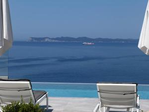 two chairs sitting on a patio overlooking the water at Villa Veneti in Pérdika